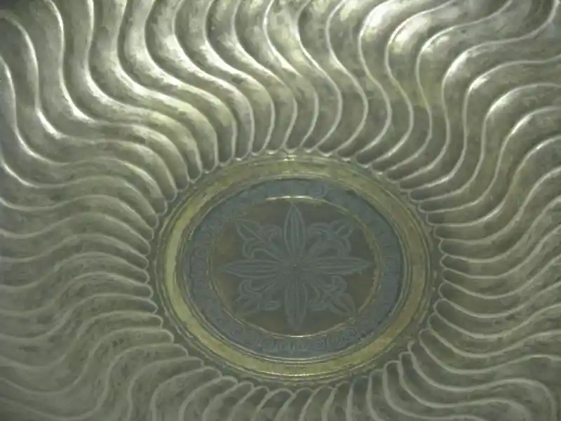 Metal dish, wavy sun rays, solar symbol in the center